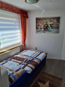 1 dormitorio con 1 cama y una ventana con flores en Ferienhaus Mandy, en Müllrose