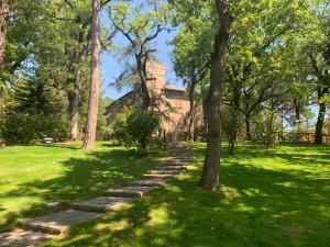 un chemin dans un parc arboré et un bâtiment dans l'établissement Castello Cortevecchio, à Gubbio