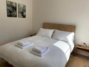 a bedroom with a white bed with two towels on it at Number 27, Swanpool in Falmouth