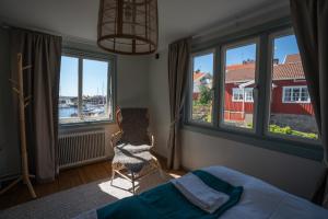 1 dormitorio con cama, ventanas y silla en Mollösunds Wärdshus en Mollösund