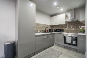 a kitchen with white cabinets and stainless steel appliances at Hotl Aparts Huddersfield Central in Huddersfield