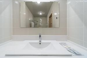 a white bathroom with a sink and a mirror at AVS Hotel in Yekaterinburg