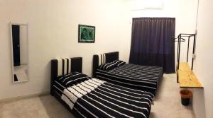 Dos camas una al lado de la otra en una habitación. en Panda Homestay, en Seremban