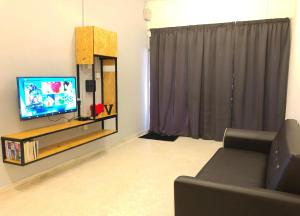 Una sala de estar con un sofá y un televisor. en Panda Homestay, en Seremban