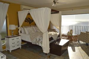 a bedroom with a bed and a canopy at Harbourview Lodge in Gordonʼs Bay