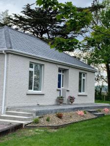 Casa blanca con porche y escaleras en un patio en WILLOW COUNTRY COTTAGE, en Killarney