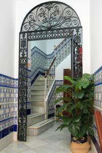 uma escada com um portão numa casa com azulejos azuis e brancos em Hostal Colón em Cádis