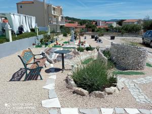 a garden with a bench and a table and plants at Holiday home Villa Anny in Brodarica
