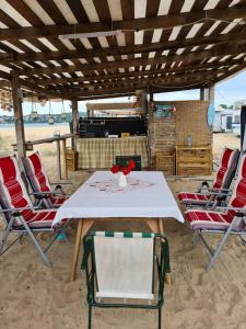 uma mesa e cadeiras numa praia com uma mesa e cadeiras brancas em Ultimate Caravan Experience - 1st Line Gradina em Sozopol