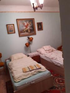 Balogh vendégház II في سيجد: سريرين توأم في غرفة مع صور على الحائط