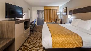 Habitación de hotel con cama y TV de pantalla plana. en Best Western Central Inn, en Savannah