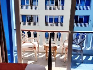 a balcony with chairs and tables on a building at Cowrie Shell Beach Apartments Official in Bamburi