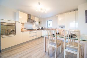 eine Küche mit weißen Schränken und einem Tisch und Stühlen in der Unterkunft Luxury Riverview City Centre Apartment in Glasgow