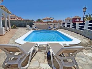 een zwembad met twee stoelen en een tafel en een zwembad bij Vv JARA in Caleta De Fuste