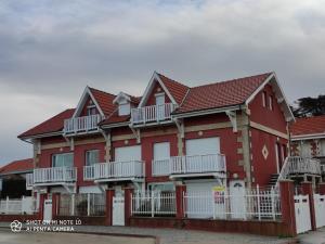a red and white house with white balconies at Soulac Côté Plage - Devant l'océan in Soulac-sur-Mer