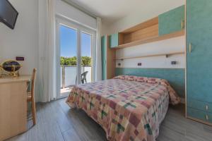 a bedroom with a bed and a desk and a window at Residence Renadoro in Cervia