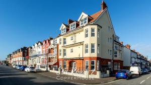 a row of houses on a street with parked cars at Beautiful apartments on the sea front - Sea Road 2 in Felixstowe