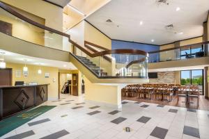 un gran vestíbulo con escalera, mesas y sillas en Quality Inn & Suites Florence - Cincinnati South en Florence