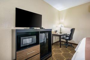 a hotel room with a television and a desk with a chair at Quality Inn & Suites Florence- Cincinnati South in Florence
