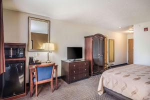a hotel room with a bed and a desk and a television at Quality Inn & Suites Eldridge Davenport North in Eldridge