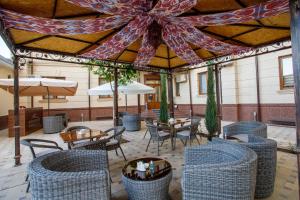 eine Terrasse mit Stühlen, Tischen und Sonnenschirmen in der Unterkunft Navruz Hotel Tashkent in Taschkent