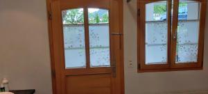 a room with a wooden door and three windows at Mountain Village Room in Habkern