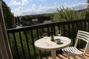 una mesa con 2 copas y una botella de vino en el balcón en Pampita, en Villers-sur-Mer