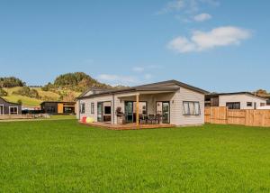 a small house on a yard with a green lawn at Seabliss - Cooks Beach Holiday Home in Cooks Beach