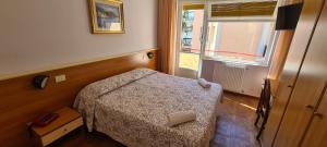 a small bedroom with a bed and a window at Hotel Colibrì in Finale Ligure