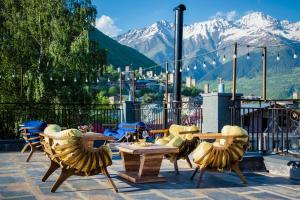 un patio con tavoli e sedie con montagne sullo sfondo di Hotel Mestia Inn a Mestia