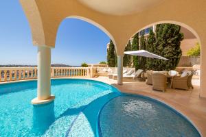 聖蓬薩的住宿－Meerblick Villa "Buena Vista" in Santa Ponsa, Mallorca，阳台的游泳池配有椅子和遮阳伞