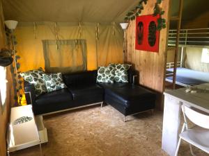 a living room with a couch and a bed in a tent at Safaritent in Hornsterzwaag