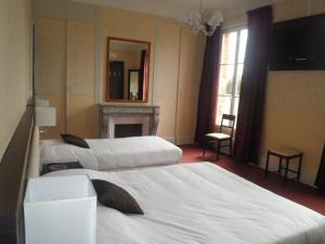 una camera d'albergo con tre letti e un camino di Logis Hotels Restaurants- Villa des Bordes a Cléry-Saint-André