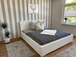 a white bed in a room with a striped wall at Ferienwohnung Bergblick in Thale