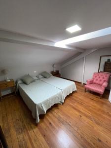 a bedroom with a bed and a pink chair at Atico El Puerto in Luarca