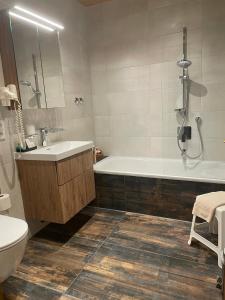 a bathroom with a tub and a sink and a toilet at Hotel Restaurant Neu Meran in Bad Reichenhall +39 photos
