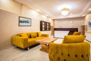 uma sala de estar com sofás amarelos e uma televisão em Hotel Mestia Inn em Mestia