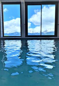 - une piscine avec des fenêtres offrant une vue sur les montagnes dans l'établissement Hotel Emeraude, à Peisey-Nancroix