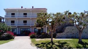 a white house with trees in front of it at Apartments Branko in Nin