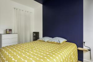 a bedroom with a yellow bed with a blue wall at MANGIN appartement moderne et chaleureux au coeur de Nantes in Nantes