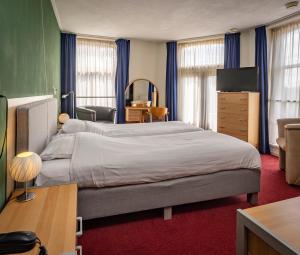 a bedroom with a large bed and a television at Hotel 't Gemeentehuis in Bedum