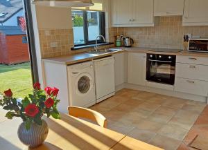 a kitchen with a washing machine and a table with a vase of flowers at Beachside Avenue Holiday Home No 15 in Courtown