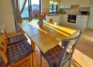 cocina con mesa de madera y sillas en Beachside Avenue Holiday Home No 15, en Courtown