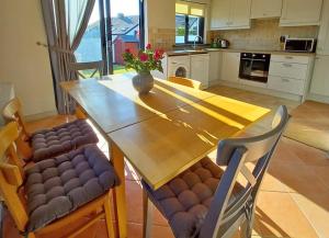 a kitchen with a wooden table and chairs at Beachside Avenue Holiday Home No 15 by Trident Holiday Homes in Courtown