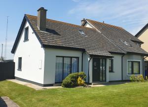 a white house with a black roof at Beachside Avenue Holiday Home No 15 by Trident Holiday Homes in Courtown +16 photos