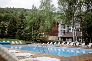 ein Pool mit weißen Stühlen und ein Gebäude in der Unterkunft Yaremche Club Hotel in Jaremtsche