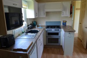uma pequena cozinha com um fogão e um lavatório em Golden Palm Resort Sherwood 6 Berth Club Tropicana Chapel St Leonards em Skegness