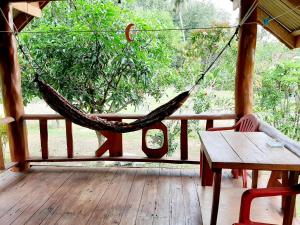 a hammock on a porch with a table and a bench at Gardenhomeresortkohjum in Ko Jum