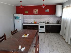 cocina con mesa de madera y nevera blanca en cabaña La Soñada, en Junín