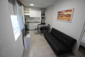un salon avec un canapé noir et une cuisine dans l'établissement ATICO OLD TOWN -La Nonna, à Alicante